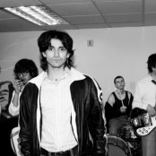 four men stand in a band practice room